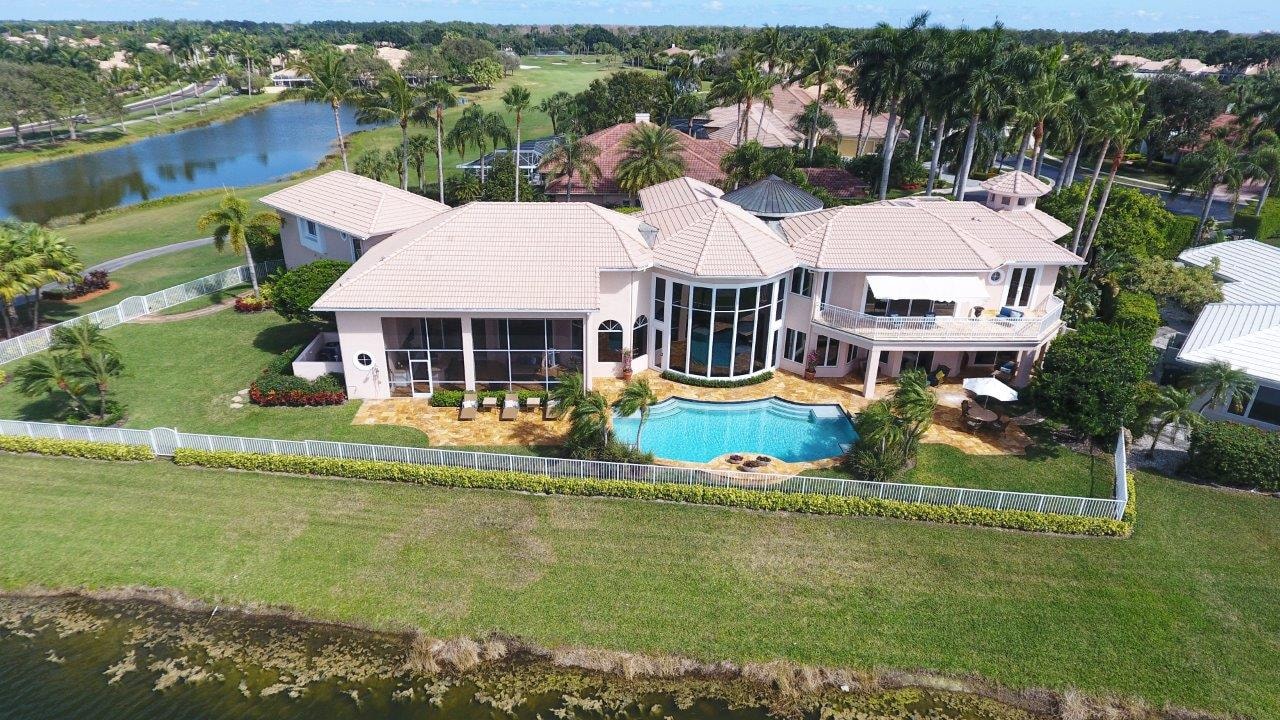 Aerial view of luxury estate with pool, golf course, and waterfront views
